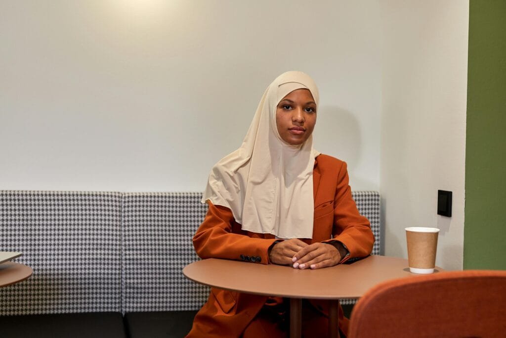 pexels-photo-10341453-10341453 Well-dressed woman in a hijab enjoying coffee at a cafe, sitting comfortably indoors.