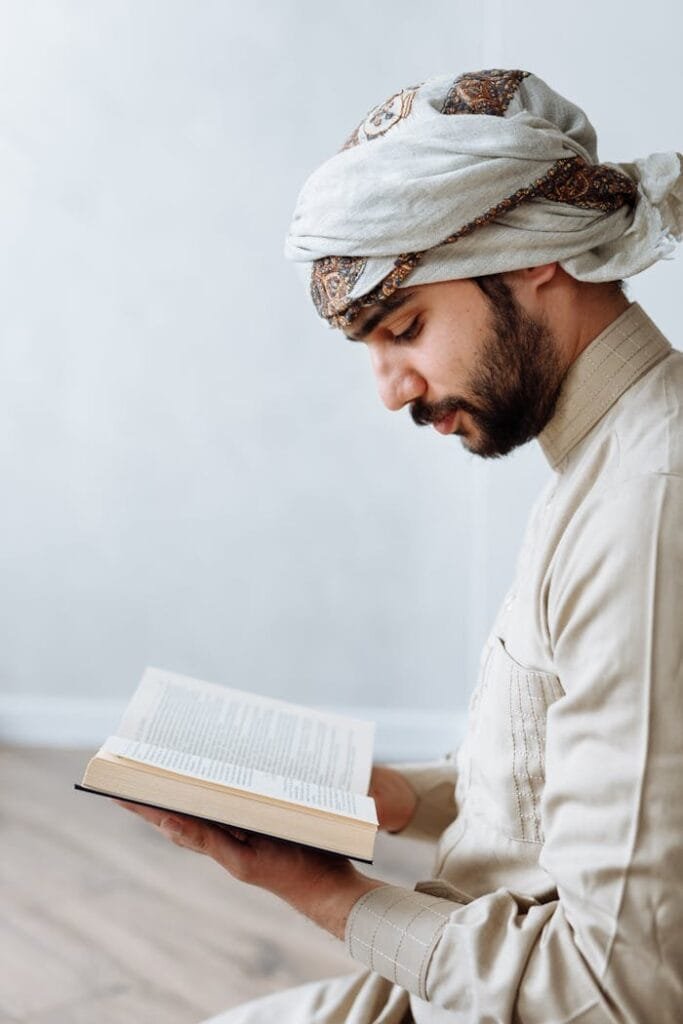 pexels-photo-7957071 Man in traditional attire peacefully reading Quran indoors, symbolizing Islamic devotion.